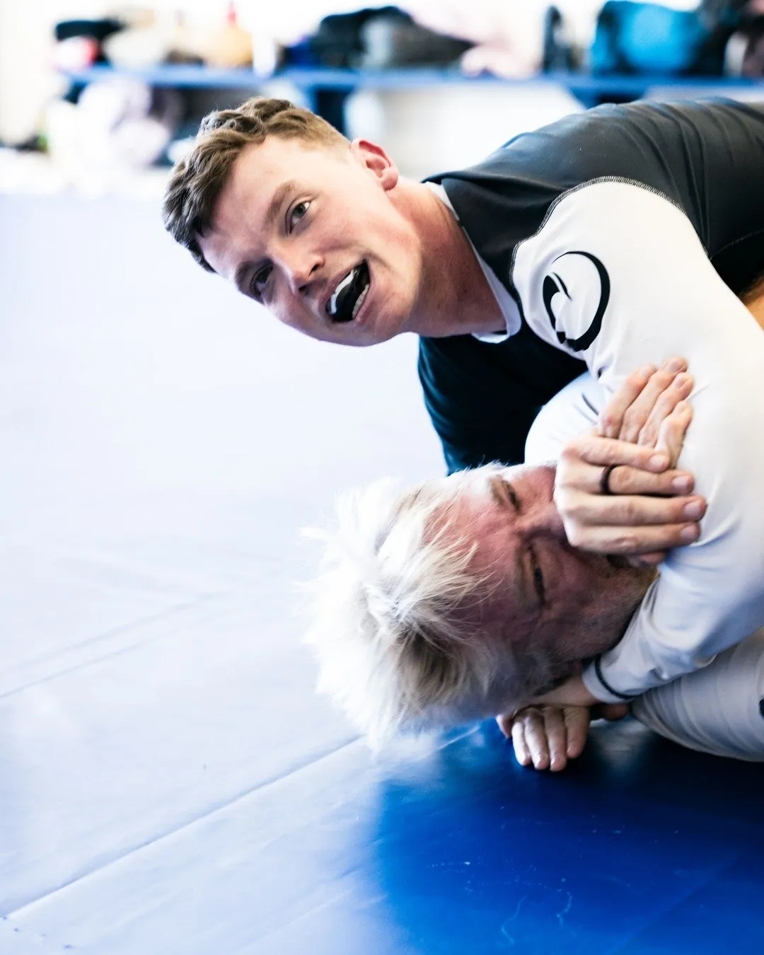 Two training partners grinning mid-roll during a no-gi American Jiu-Jitsu class at Egley Train Academy