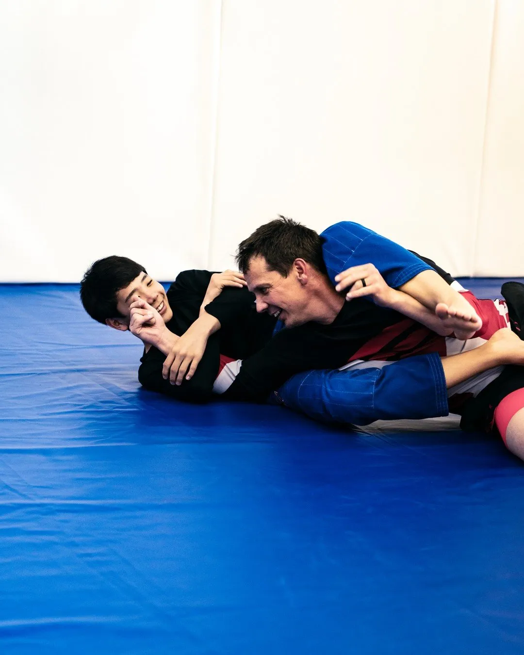Two training partners laughing together on the mat during American Jiu-Jitsu class at the Boise Academy